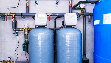 Two water softeners are connected to a pipe.