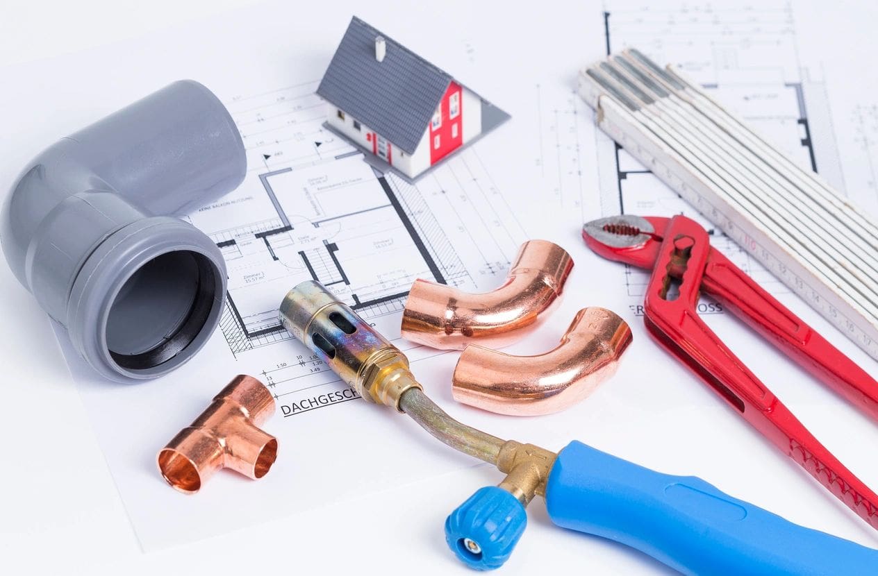A variety of plumbing tools are laying on top of a plan.